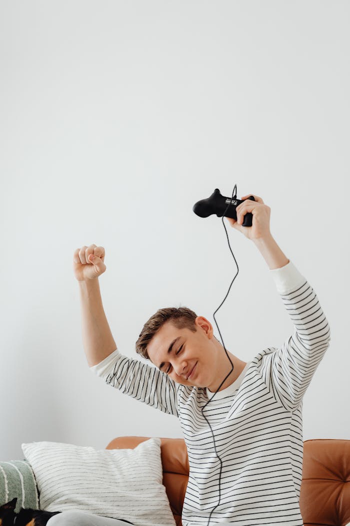 Teen enjoying a winning moment while playing video games indoors, showing happiness and excitement.