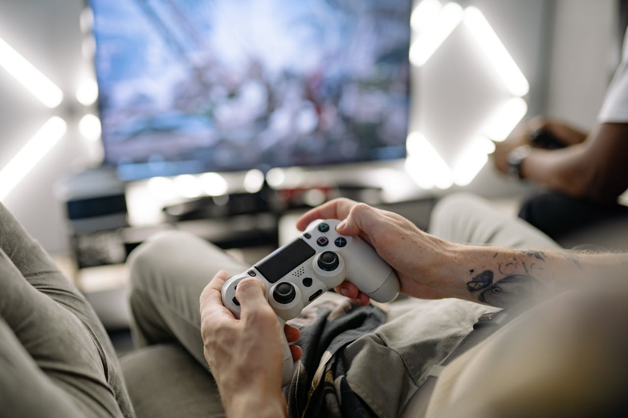 Hands holding a video game controller in a modern living room, playing on TV.